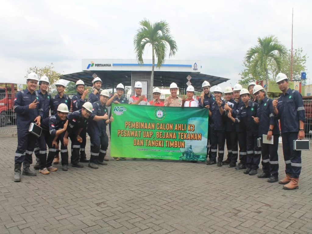 Peserta pelatihan ahli K3 PUBT berfoto bersama di lokasi praktik industri dengan mengenakan APD lengkap dalam program pembinaan pesawat uap, bejana tekan, dan tangki timbun di Yogyakarta