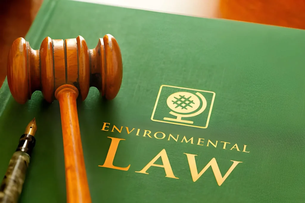 Buku Environmental Law dengan palu hakim sebagai simbol regulasi KLH terbaru yang mengatur kepatuhan dan peraturan lingkungan hidup di Indonesia.