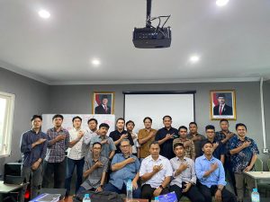 Pembinaan Ahli K3 PUBT Hari Kedua di ruang kelas pelatihan, menampilkan peserta dan instruktur berfoto bersama dengan sikap tangan di dada, dilengkapi layar proyektor, papan tulis, serta suasana pembelajaran yang profesional dan kondusif.
