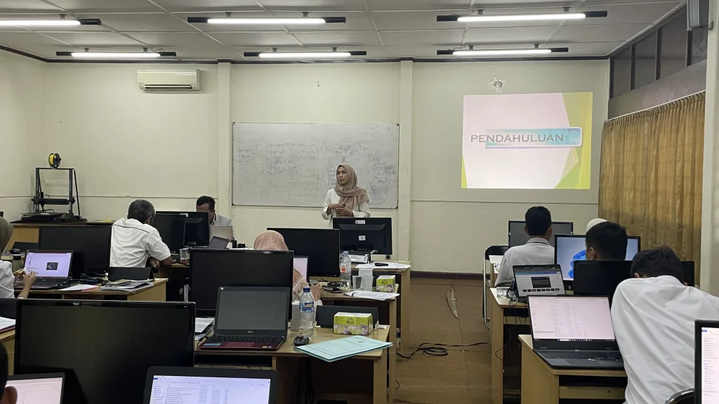 Suasana Uji Kompetensi Sertifikasi BNSP di ruang pelatihan BLPT Yogyakarta, peserta mengikuti asesmen dengan laptop sementara instruktur mempresentasikan materi di depan kelas.